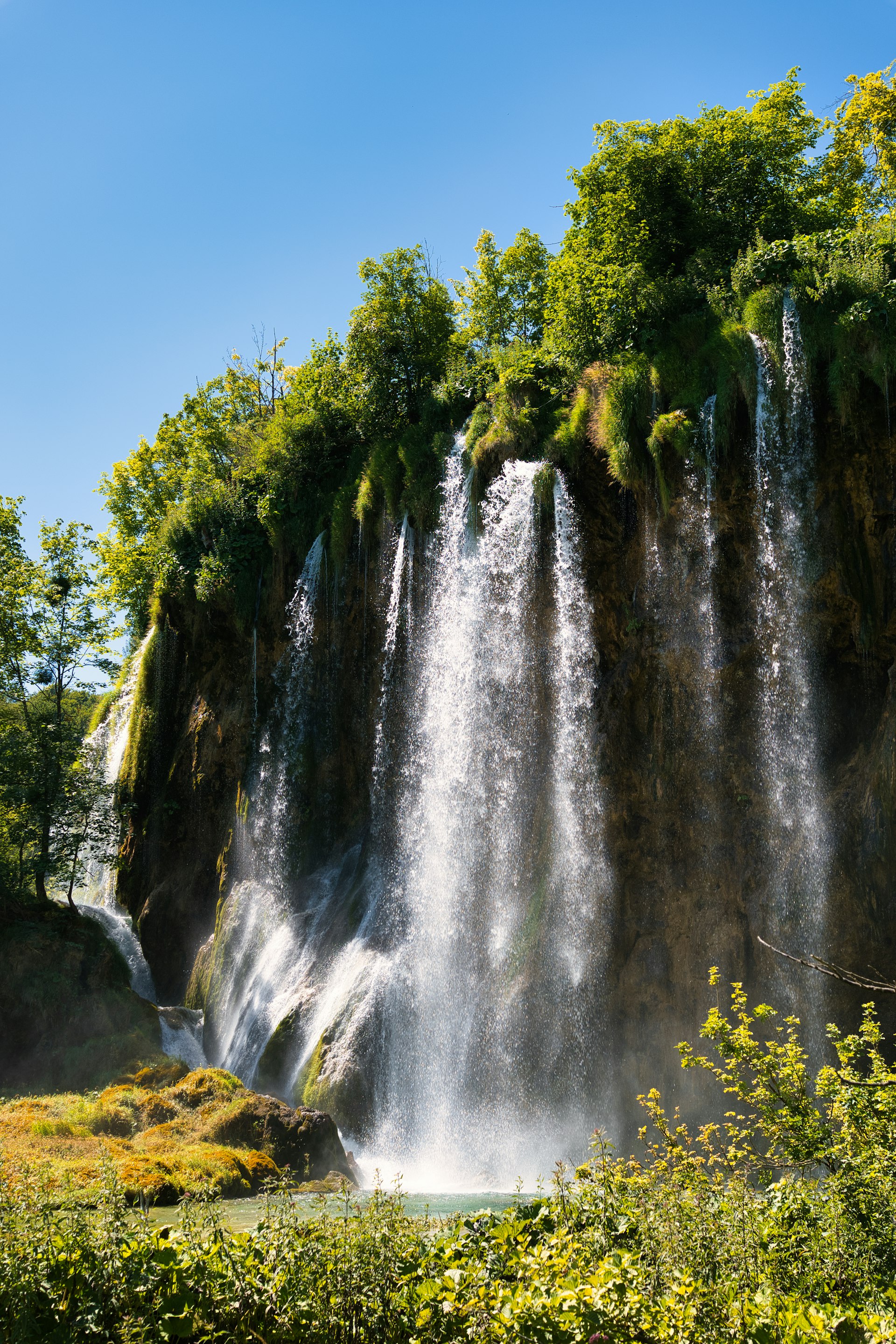 Lush waterfall cascading down a rocky cliffside at Plitvice Lakes in summer