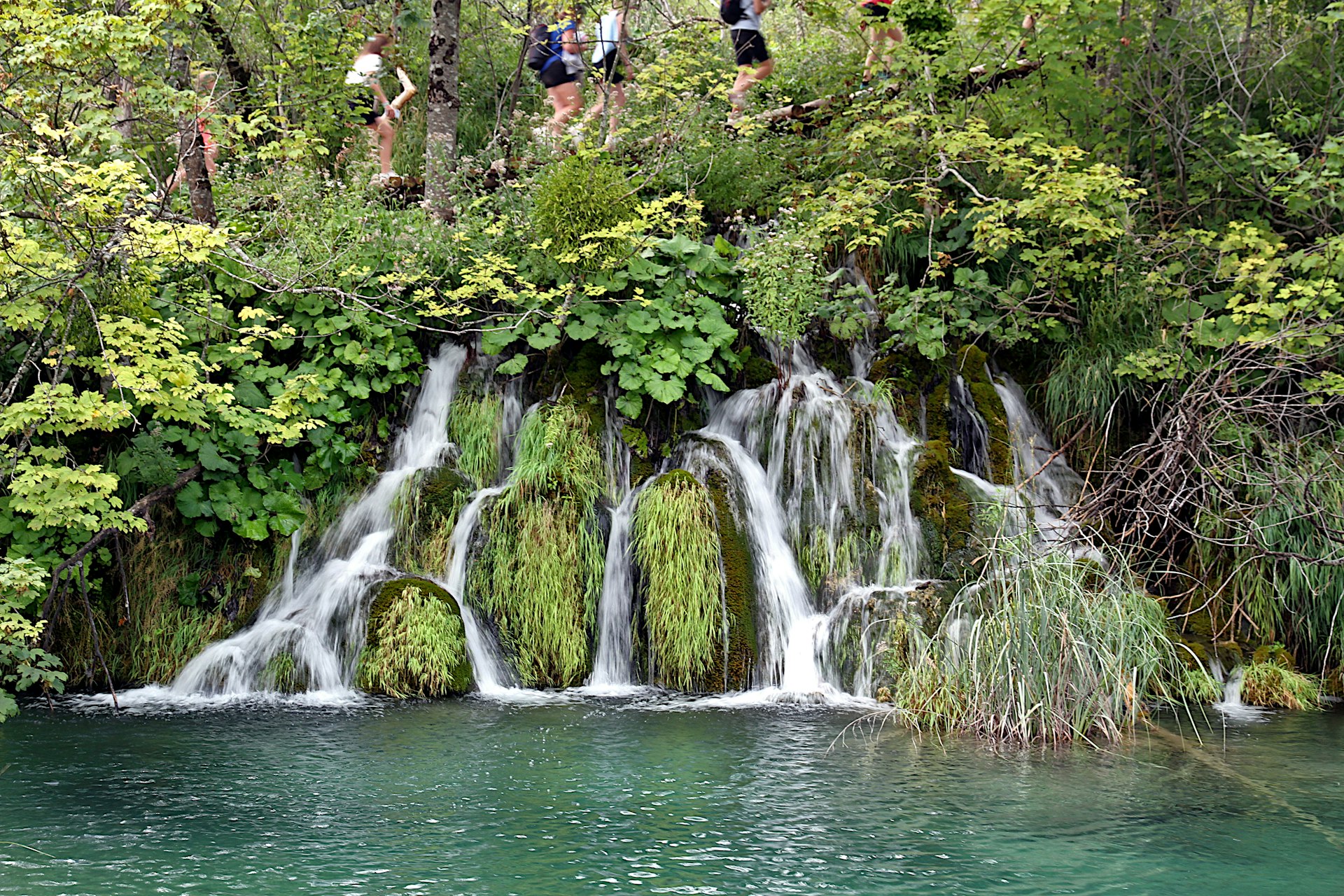 Small waterfalls at Plitvice Lakes National Park in summer with visitors