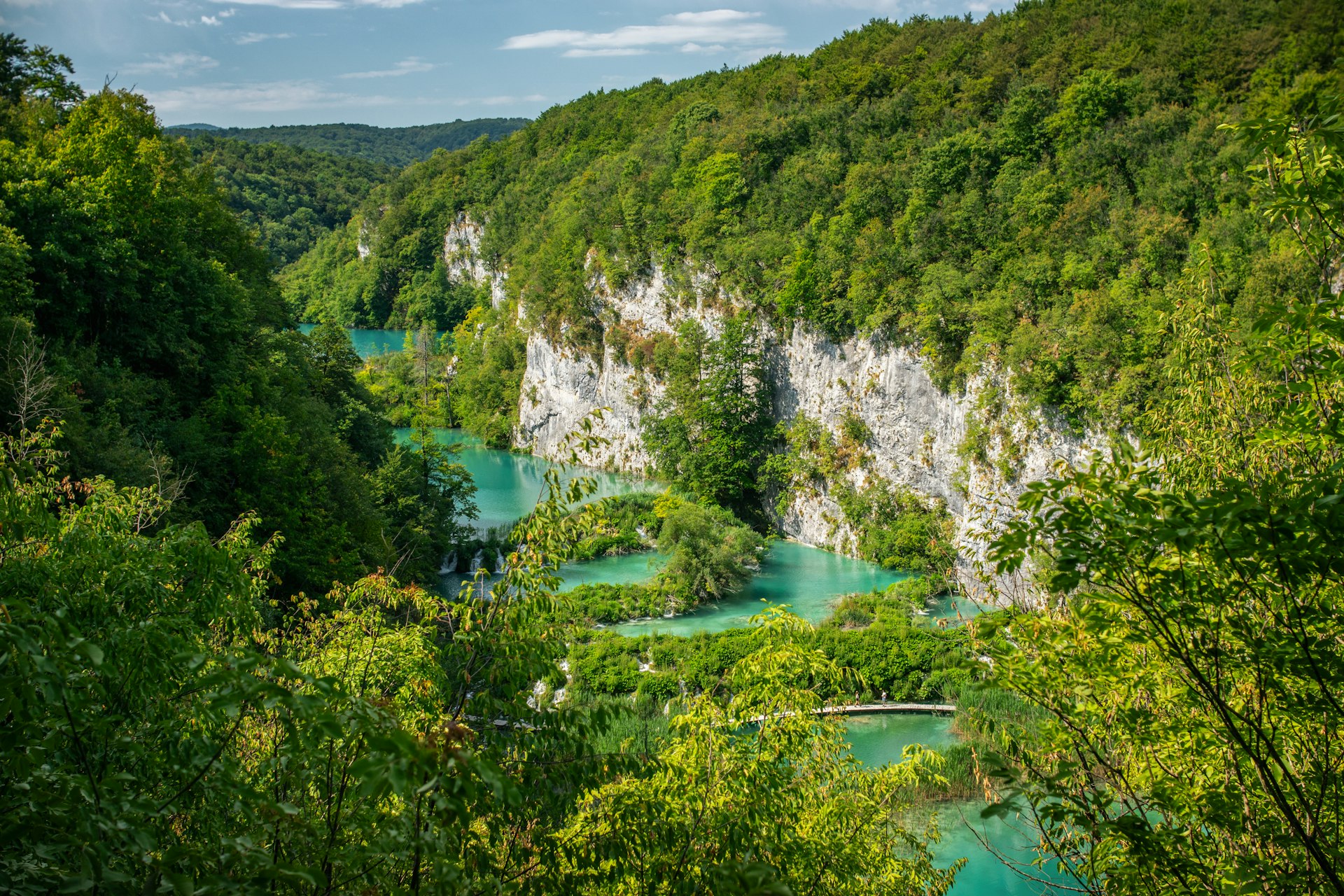 Turquoise lakes winding through a lush green forested canyon at Plitvice Lakes